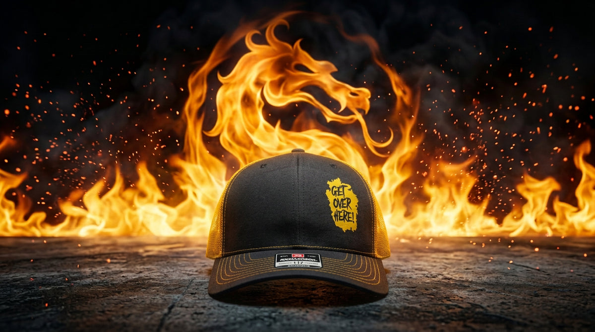 "Get Over Here!" black and gold trucker hat in front of Mortal Kombat dragon flames