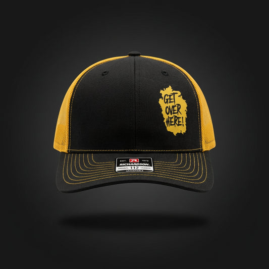 Scorpion "Get Over Here!" Richardson 112 trucker hat, black crown and bill with gold mesh back, gold stitching, and yellow splash print on the front panel — front view
